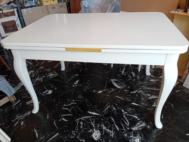 Il tavolo dopo l'intervento di restyling; anch'esso nelle tonalità del bianco caldo con stesura di foglia oro in corrispondenza delle allunghe laterali. Il tavolo dopo l'intervento di restyling; anch'esso nelle tonalità del bianco caldo con stesura di foglia oro in corrispondenza delle allunghe laterali.